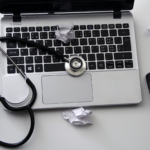 Laptop computer with wireless mouse and stethoscope and crumpled papers