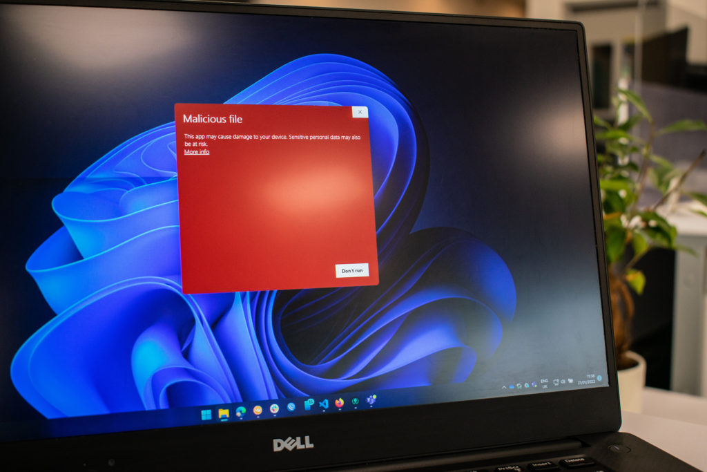 Windows laptop computer with a malicious file warning up on the screen