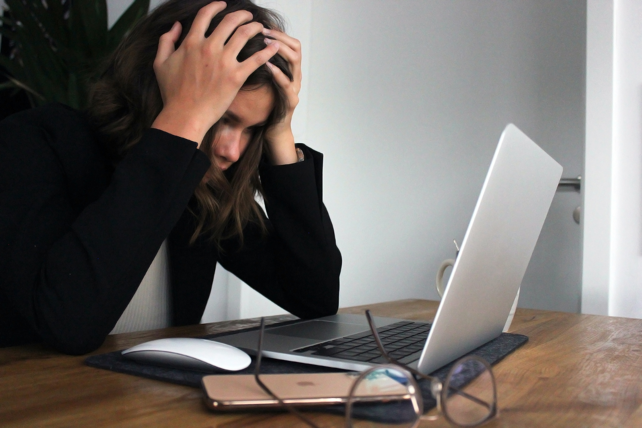 photo of a woman very frustrated with her laptop sitting on a table in front of her