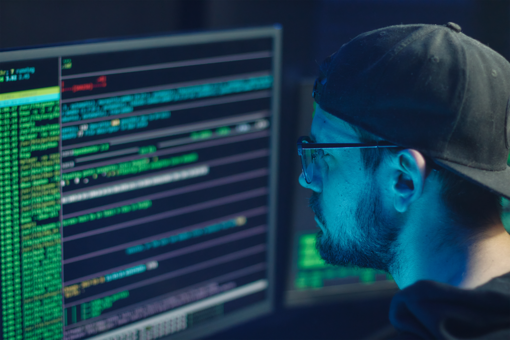 Photograph of a man who is programming a computer in a dark room